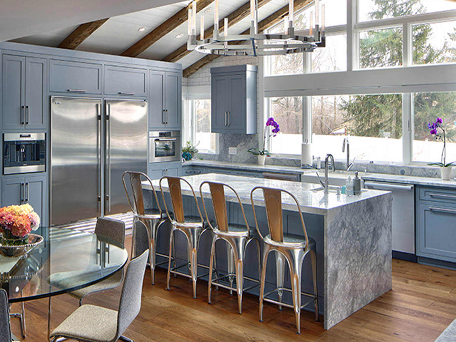 A bright, airy kitchen with marble countertops and wide windows looking out into a snowy yard